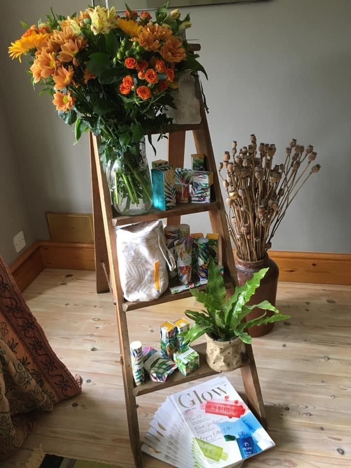 A tropic skincare display using a stepladder as a shelf featuring real flowers